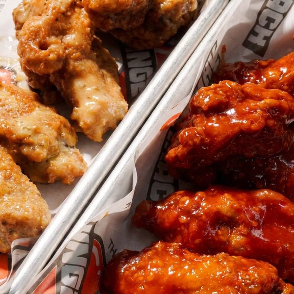 Two trays of Wingz chicken wings, one with a light sauce and one with a spicy red sauce.